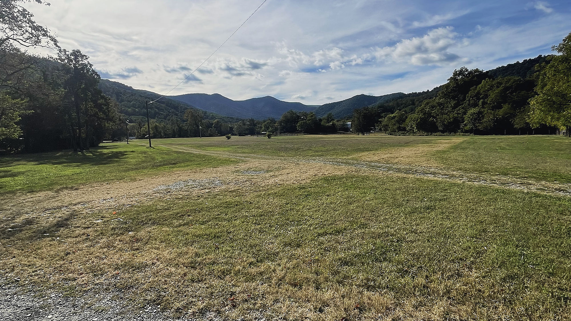 An open valley under wooded ridges and a wide blue sky